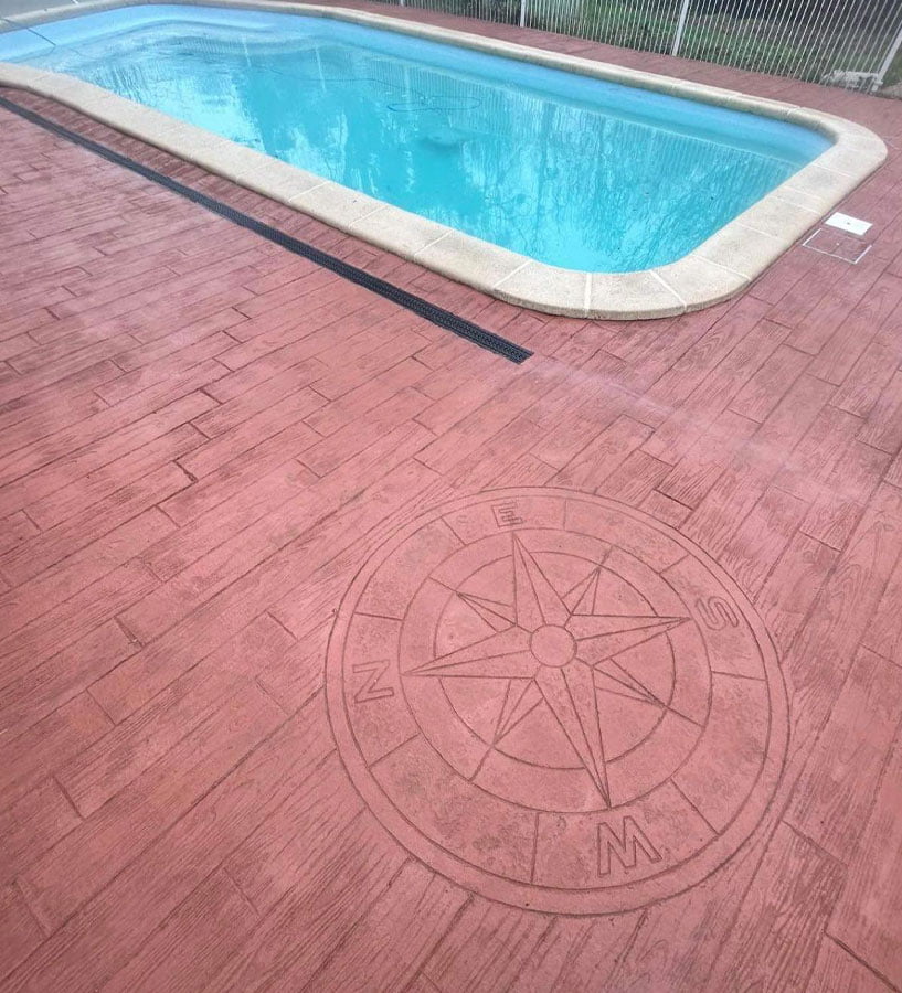 La piscine d'un de nos clients, réalisée par LCH Maçonnerie, avec une boussole en béton imprimé aspect bois vieilli qui donne du cachet à l’espace extérieur.